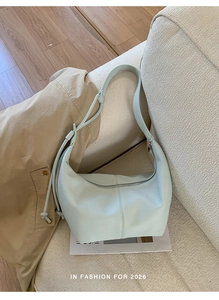 Detail view of mint green crescent bag with soft lychee leather texture and strap knot
