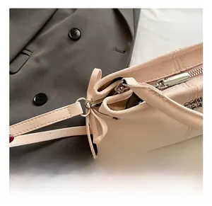 Close-up of light pink leather bag featuring silver hardware hooks and smooth zipper details