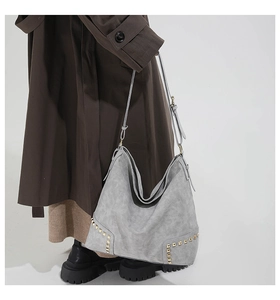 Dettaglio della grande borsa hobo grigia con borchie dorate e tracolla regolabile