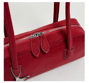 Detail of red leather bowling bag featuring silver star charm and smooth dual zippers