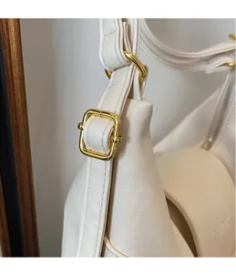 Vista macro dettagliata della fibbia in metallo dorato su una borsa tote in pelle bianca