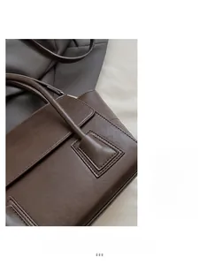 Detail of brown leather handbag showing precise stitching and soft matte texture