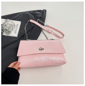Détail de la texture plissée brillante et du fermoir rotatif argenté sur le sac rose