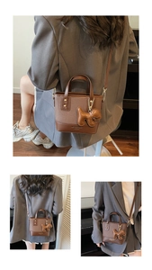 Détails d'un sac seau marron avec ferrures dorées et charmant pendentif chien