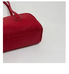 Detail of red leather handbag showing reinforced bottom with precision stitching