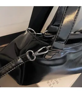 Detail of durable silver swivel hook and metal zipper on black patent leather handbag