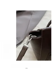 Macro detail of silver metal hooks and premium stitching on a dark brown leather handbag