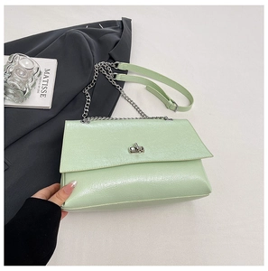 Détail du sac en cuir verni vert clair avec bandoulière chaîne argentée et fermoir rotatif