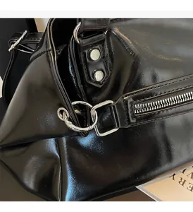 Close-up of shiny black shoulder bag with polished silver hardware and rivet details