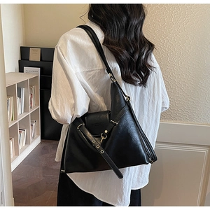Détail du sac cabas noir avec bandoulières à œillets dorés et soufflets latéraux pliés