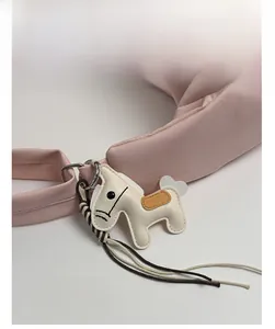 Close-up of a creative horse-shaped leather charm attached to a pink shoulder handbag