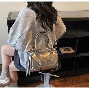 Detailed macro view of silver metallic Boston bag with rivet accents and long leather tassels
