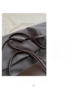 Detail of adjustable metal buckle and fine stitching on dark brown leather handbag