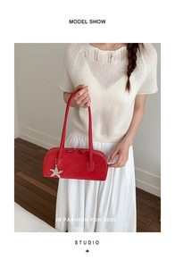 Detail of red suede baguette bag with long handle and silver star charm accessory