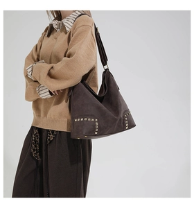 Dettaglio della borsa tote vintage marrone con borchie dorate su pelle scamosciata opaca
