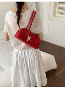 Detail view of red suede handbag with silver star charm worn by a model