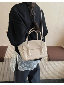 Detail of minimalist beige faux leather handbag showing fine texture and sleek shoulder strap