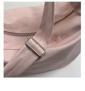 Close-up of adjustable strap buckle and soft leather texture on pink crossbody tote bag