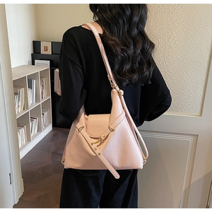 Sac à bandoulière rose en cuir grainé avec boucle dorée porté par un mannequin