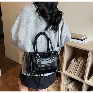 Retro black Boston bag with metallic rivets and long tassels shown in a lifestyle scene