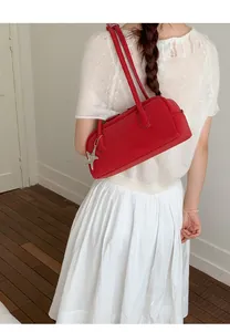 Detail view of red leather bowling bag with silver star charm worn on shoulder