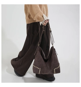 Dettaglio della grande borsa tote in pelle scamosciata marrone con borchie dorate sul fondo