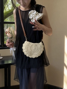 Beige hollow woven straw shoulder bag in semi-circle saddle shape with leather strap