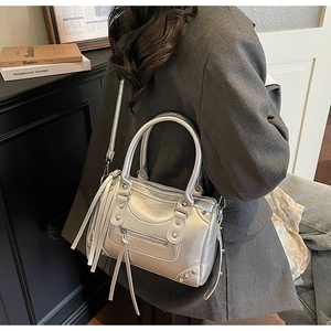 Detail of silver metallic Boston bag with rivet studs and long fringe zipper pulls