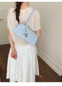 Close-up of light blue bowling bag with silver star pendant on smooth leather surface