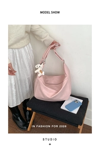 Close-up of pink soft leather hobo bag with white horse charm in a minimalist studio setting