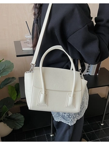 Detail of a chic cream white handbag with a classic flap design and sturdy double handles