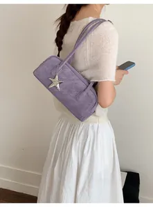 Detail of purple suede baguette bag with silver starfish charm and dual shoulder straps