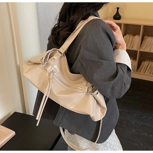 Detail view of beige glossy PU leather bag with long double tassels and silver metal rings