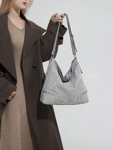 Borsa hobo grigia con borchie dorate e tracolla regolabile indossata da una modella