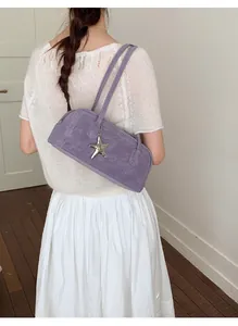 Detail of purple vintage textured bowling bag with silver starfish charm shown on shoulder