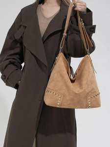 Borsa hobo color cammello con borchie dorate e tracolla regolabile su look autunnale
