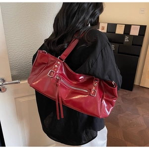 Detail of dark red high-gloss faux leather shoulder bag with silver tassels and hardware