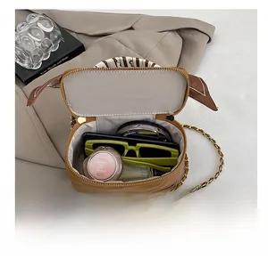 Internal view of a quilted brown box bag showing space for sunglasses and perfume