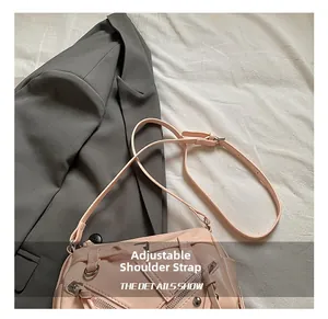 Detail of pink baguette bag showing adjustable shoulder strap and silver metal zipper