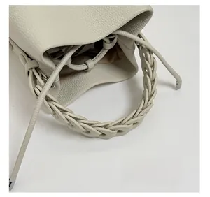 Detail of lychee pattern leather bucket bag with woven handle and drawstring closure