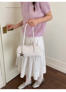 Close-up of a white leather bowling bag featuring a decorative silver star-shaped pendant