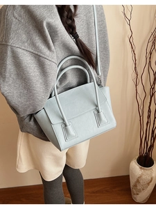 Detail of mint green crossbody bag with rounded handles and adjustable shoulder strap