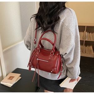 Detailed back view of a burgundy motorcycle style bag with silver studs and long tassels