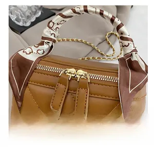 Detail of smooth golden metal double zippers on a brown quilted leather mini bag