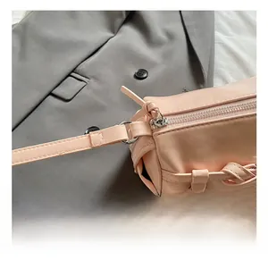 Close-up of pink cylinder bag with silver ring hook and zipper on grey suit background