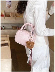 Détail du mini sac Boston rose en cuir PU avec charm ours et bandoulière tissée assortie
