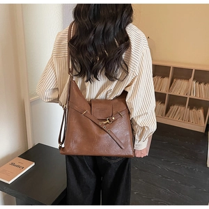 Dettaglio di una borsa a tracolla in pelle marrone con fibbia indossata da una modella