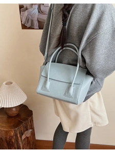 Detail of light blue minimalist handbag with textured PU leather and top handle