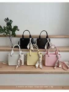 Detailed view of square faux leather handbags with woven handles and decorative scarves