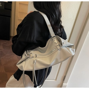 Detail of light grey glossy faux leather shoulder bag with tassels and decorative zipper